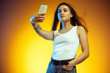 Image showing Portrait of young caucasian woman isolated on gradient yellow studio background