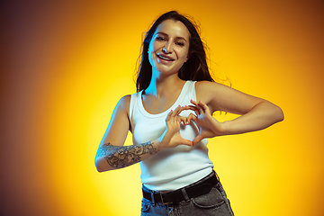 Image showing Portrait of young caucasian woman isolated on gradient yellow studio background