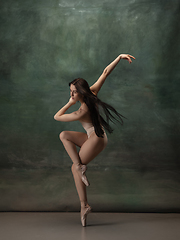 Image showing Young graceful tender ballerina on dark green studio background