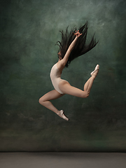 Image showing Young graceful tender ballerina on dark green studio background