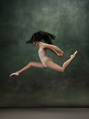 Image showing Young graceful tender ballerina on dark green studio background