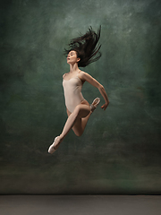 Image showing Young graceful tender ballerina on dark green studio background