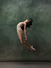 Image showing Young graceful tender ballerina on dark green studio background