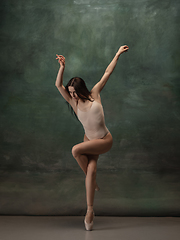 Image showing Young graceful tender ballerina on dark green studio background