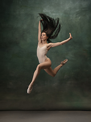 Image showing Young graceful tender ballerina on dark green studio background