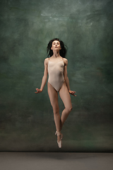 Image showing Young graceful tender ballerina on dark green studio background