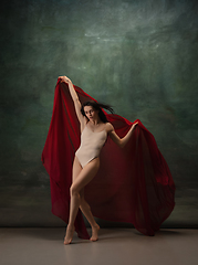 Image showing Young graceful tender ballerina on dark green studio background