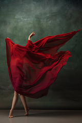 Image showing Young graceful tender ballerina on dark green studio background