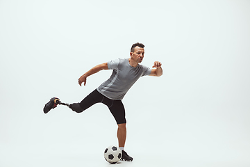 Image showing Athlete with disabilities or amputee isolated on white studio background. Professional male football player with leg prosthesis training and practicing in studio.