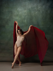 Image showing Young graceful tender ballerina on dark green studio background