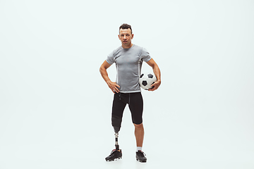 Image showing Athlete with disabilities or amputee isolated on white studio background. Professional male football player with leg prosthesis training and practicing in studio.