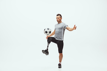 Image showing Athlete with disabilities or amputee isolated on white studio background. Professional male football player with leg prosthesis training and practicing in studio.