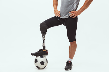 Image showing Athlete with disabilities or amputee isolated on white studio background. Professional male football player with leg prosthesis training and practicing in studio.