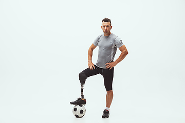 Image showing Athlete with disabilities or amputee isolated on white studio background. Professional male football player with leg prosthesis training and practicing in studio.