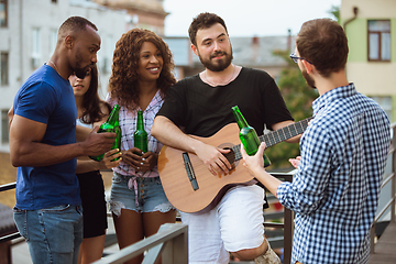 Image showing Group of happy friends having beer party in summer day. Resting together outdoor, celebrating and relaxing, laughting. Summer lifestyle, friendship concept.