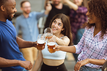 Image showing Group of happy friends having beer party in summer day. Resting together outdoor, celebrating and relaxing, laughting. Summer lifestyle, friendship concept.