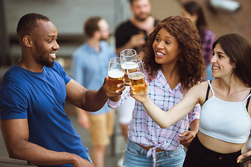 Image showing Group of happy friends having beer party in summer day. Resting together outdoor, celebrating and relaxing, laughting. Summer lifestyle, friendship concept.