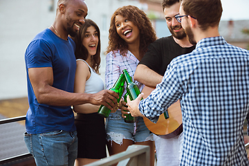 Image showing Group of happy friends having beer party in summer day. Resting together outdoor, celebrating and relaxing, laughting. Summer lifestyle, friendship concept.