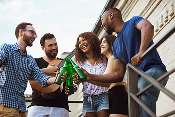 Image showing Group of happy friends having beer party in summer day. Resting together outdoor, celebrating and relaxing, laughting. Summer lifestyle, friendship concept.