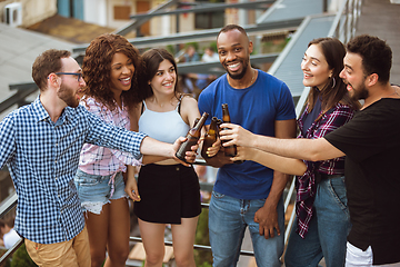 Image showing Group of happy friends having beer party in summer day. Resting together outdoor, celebrating and relaxing, laughting. Summer lifestyle, friendship concept.