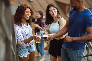 Image showing Group of happy friends having beer party in summer day. Resting together outdoor, celebrating and relaxing, laughting. Summer lifestyle, friendship concept.