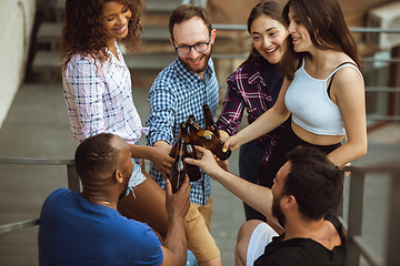 Image showing Group of happy friends having beer party in summer day. Resting together outdoor, celebrating and relaxing, laughting. Summer lifestyle, friendship concept.