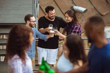 Image showing Group of happy friends having beer party in summer day. Resting together outdoor, celebrating and relaxing, laughting. Summer lifestyle, friendship concept.