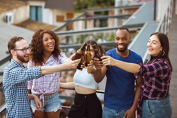 Image showing Group of happy friends having beer party in summer day. Resting together outdoor, celebrating and relaxing, laughting. Summer lifestyle, friendship concept.