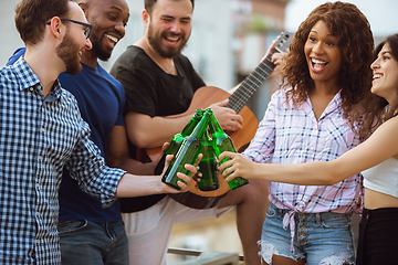 Image showing Group of happy friends having beer party in summer day. Resting together outdoor, celebrating and relaxing, laughting. Summer lifestyle, friendship concept.