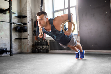 Image showing man doing push-ups on gymnastic rings in gym