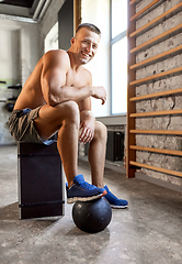 Image showing happy smiling young man with medicine ball in gym