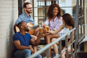 Image showing Group of happy friends having beer party in summer day. Resting together outdoor, celebrating and relaxing, laughting. Summer lifestyle, friendship concept.