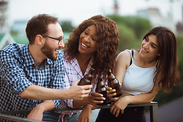 Image showing Group of happy friends having beer party in summer day. Resting together outdoor, celebrating and relaxing, laughting. Summer lifestyle, friendship concept.