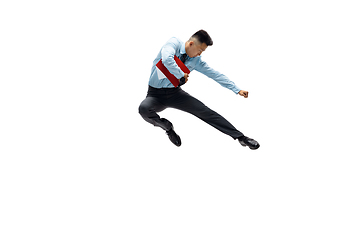 Image showing Man in office clothes practicing taekwondo on white background. Unusual look for businessman in motion, action. Sport, healthy lifestyle.