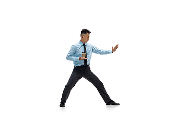 Image showing Man in office clothes practicing taekwondo on white background. Unusual look for businessman in motion, action. Sport, healthy lifestyle.