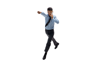 Image showing Man in office clothes practicing taekwondo on white background. Unusual look for businessman in motion, action. Sport, healthy lifestyle.