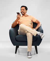 Image showing happy indian man calling on smartphone in chair