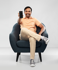 Image showing happy young indian man showing smartphone in chair