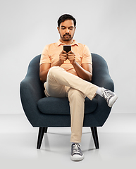 Image showing young indian man with smartphone in chair