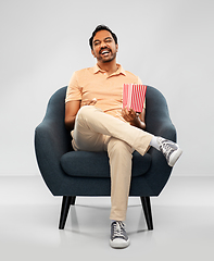 Image showing happy smiling indian man eating popcorn in chair