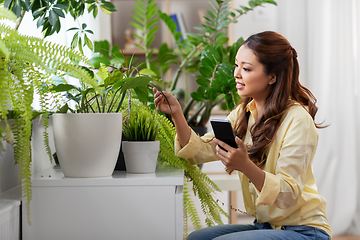Image showing asian woman with smartphone and flowers at home