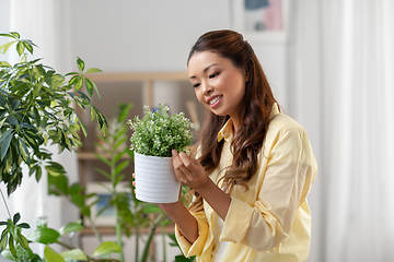 Image showing happy asian woman with flower in pot at home