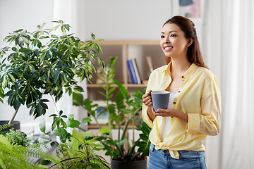 Image showing happy smiling asian woman drinking coffee at home