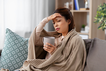 Image showing ill asian woman with headache drinking tea at home