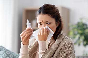 Image showing sick asian woman with nasal spray medicine at home
