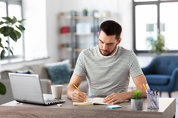 Image showing man with notebook and laptop at home office