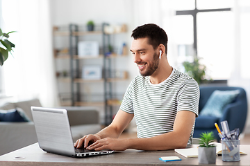 Image showing man with laptop and earphones at home office