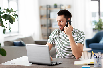 Image showing man with laptop calling on phone at home office