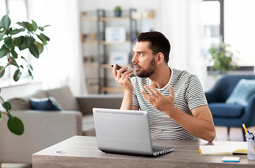 Image showing man with laptop calling on phone at home office