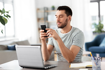 Image showing man with smartphone and laptop at home office